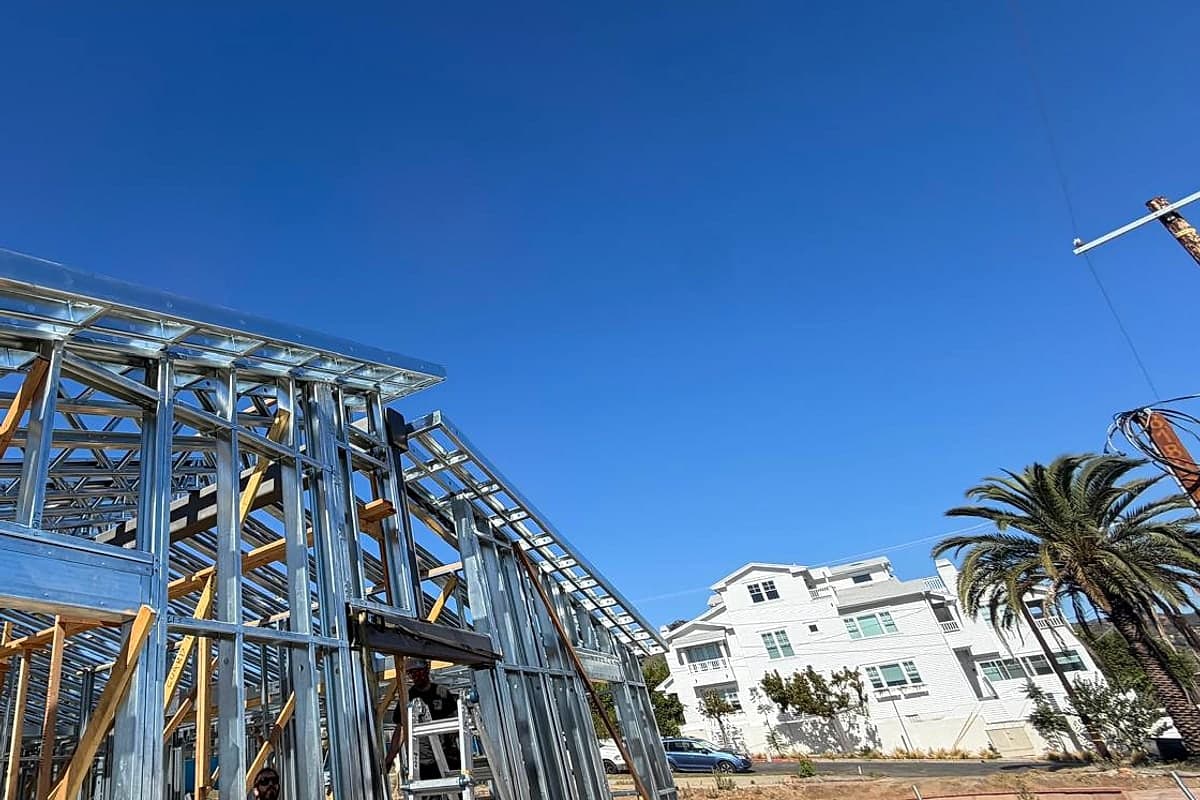 The steel roof line against a blue sky with coastal apartments and palms behind