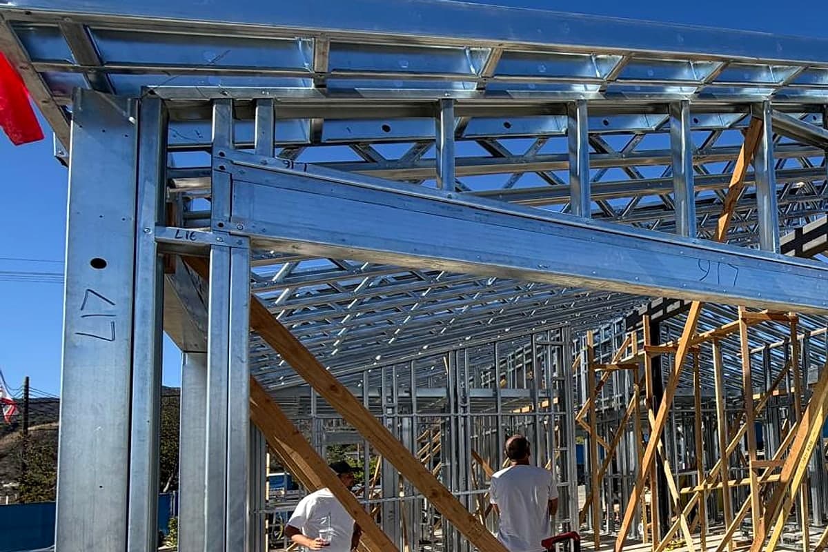 Crew working inside the steel frame among temporary wood braces