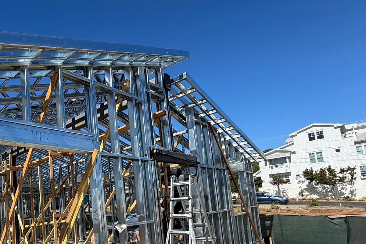 A steel header over a wide opening, a ladder and the roof framing beyond