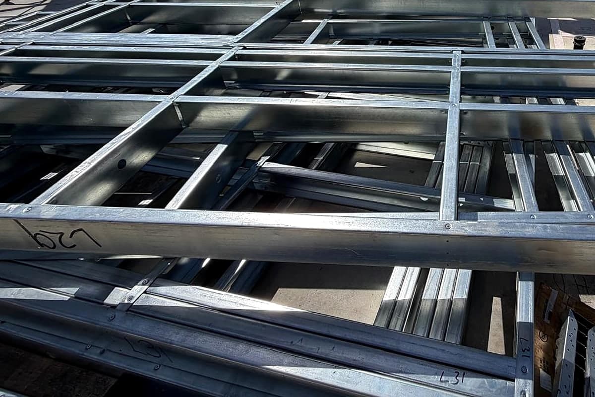 Steel studs and tracks with pre-punched holes, lying on the slab