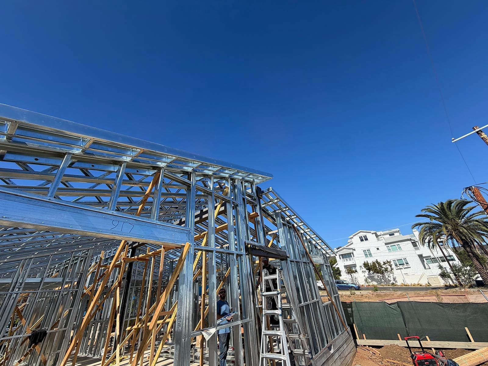 Low-angle view of the steel roof line and eave overhang of the house against a deep blue sky