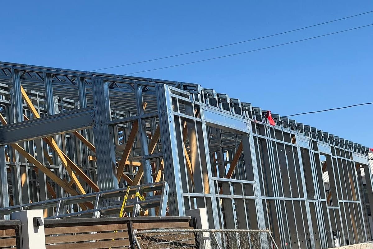 The steel-framed house seen from the street, behind a slatted fence