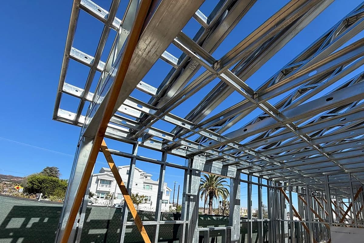 Steel roof members overhead against a blue sky, seen from inside the frame